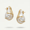 Pearl earrings with gold accents on a light beige background