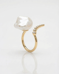 Gold bypass ring with a large pearl and diamonds on a white background